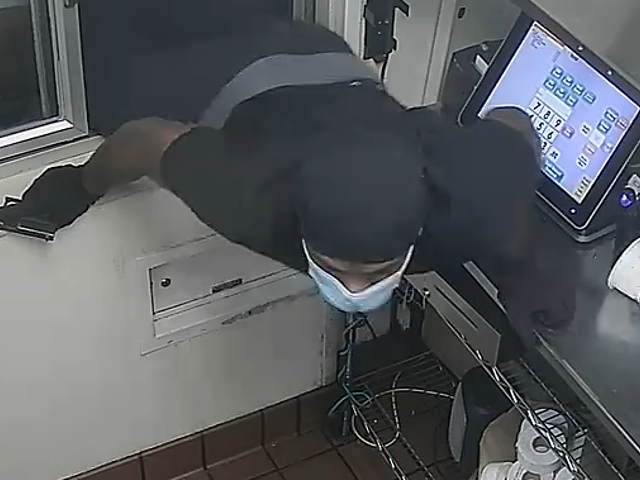 The gunman in action, climbing through the window of a St. Louis McDonald's.