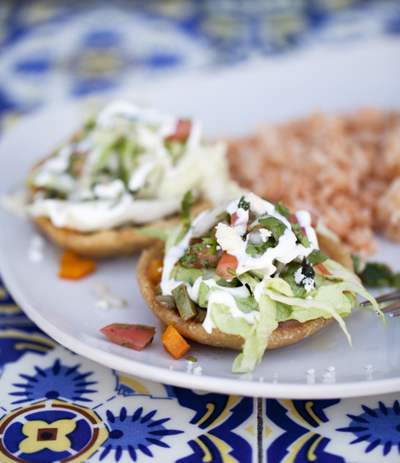 Sopes - deep fried handmade corn tortilla shells topped with steamed cactus, sauteed poblano chiles, lettuce, fresco cheese and sour cream.