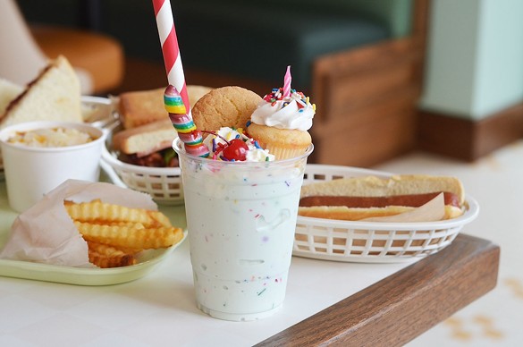 The A Very Un-Happy Birthday Freak Shake is a birthday cake shake topped with a Funfetti cupcake, whipped cream, rainbow sprinkles, a snickerdoodle cookie, a rainbow pop and a cherry.