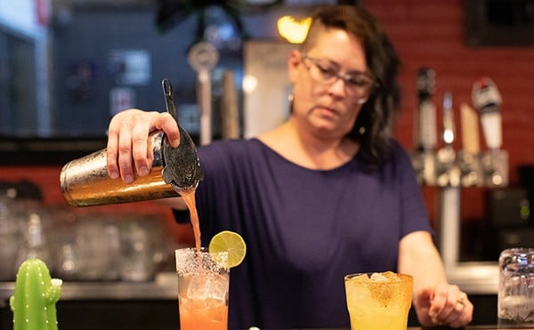 A woman bartender pours a drink.
