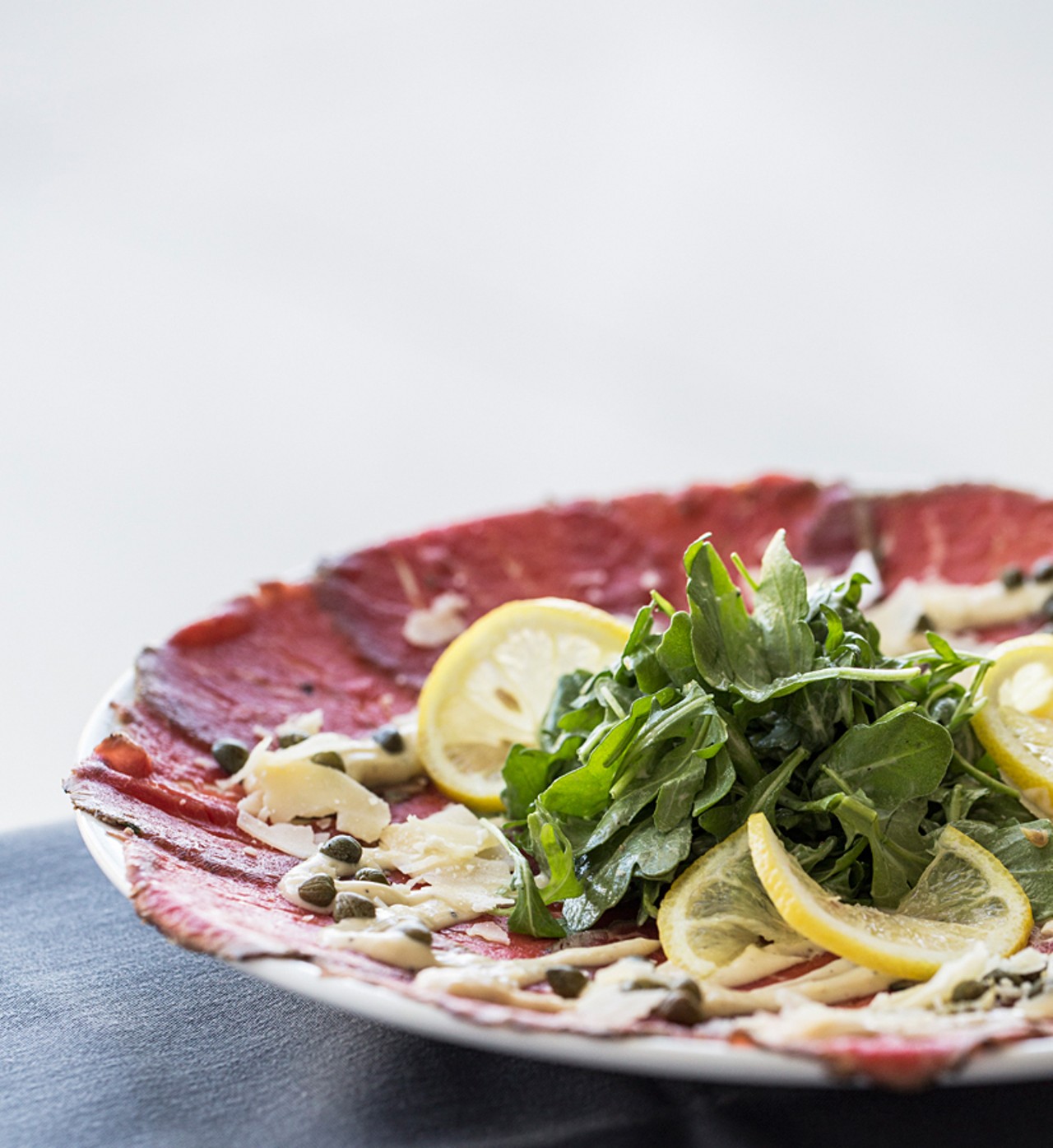 Peppered beef carpaccio: thinly sliced beef fillet, mustard dressing, arugula, shaved parmesan, capers and lemon.