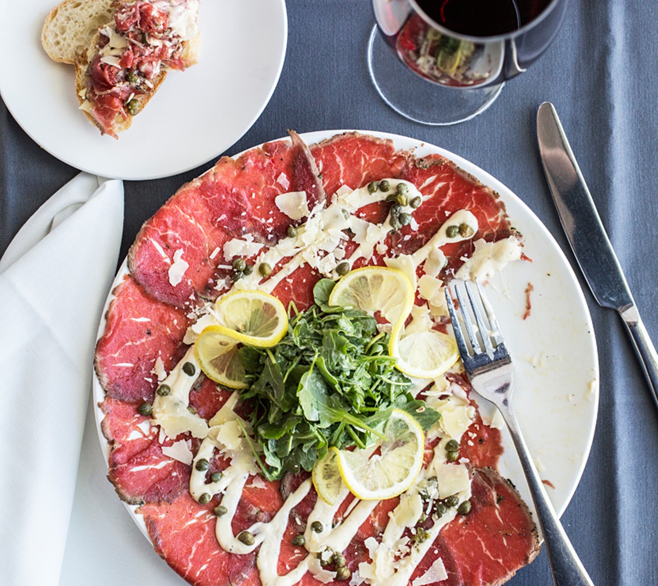 Peppered beef carpaccio: thinly sliced beef fillet, mustard dressing, arugula, shaved parmesan, capers and lemon.