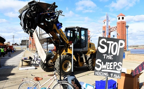 A bulldozer carries items left from a riverfront encampment near Laclede's Landing.