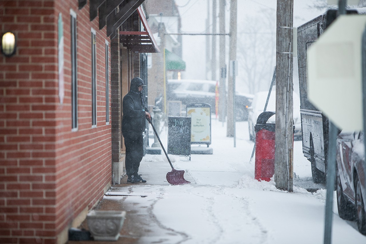 A man shovels snow in front of a business on the Hill on Friday, Feb. 16, 2024.
