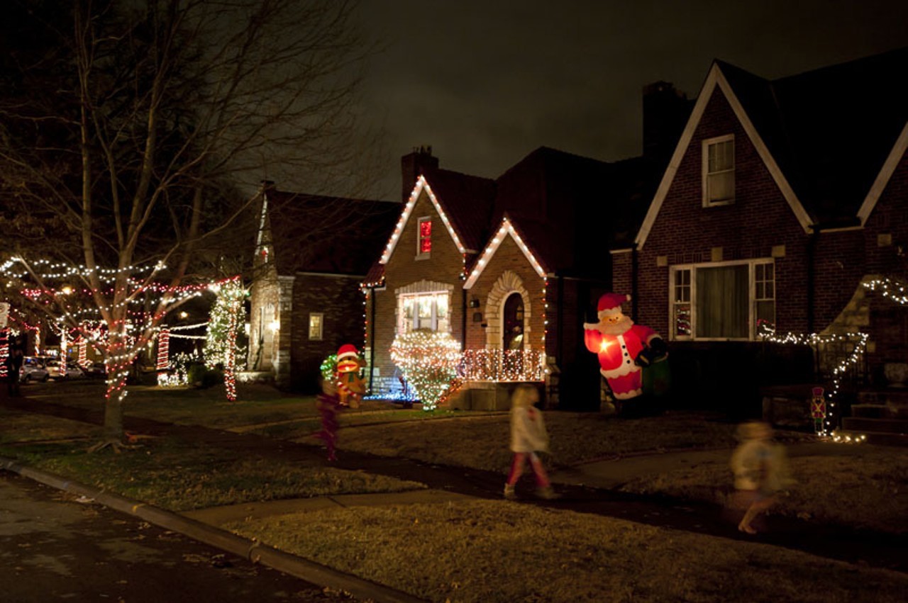 Children running past Christmas decorations on "Candy Cane Lane" in South City.