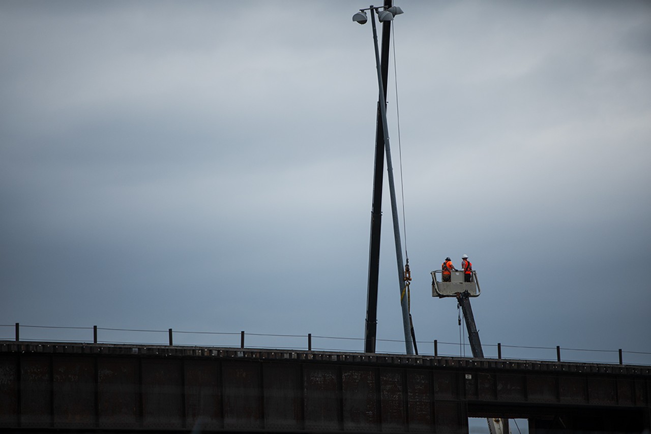 Workers stand atop of a skyjack as crews below work to flip derailed railcars upright on Tuesday, April 16, 2024.