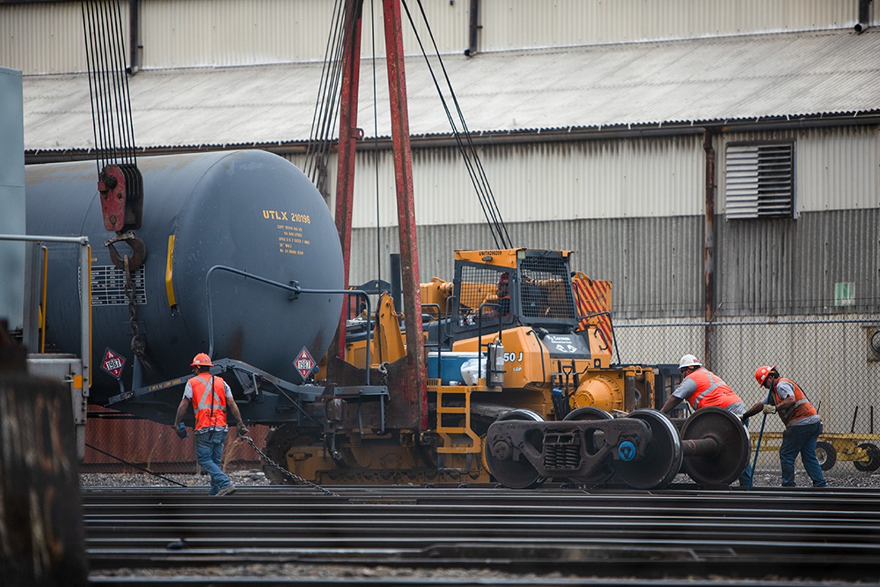 Crew members flip a railcar upright and move it along the railway.