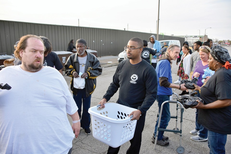 Sean Liddell hands out water outside of Biddle House, the city's primary homeless shelter. - DOYLE MURPHY