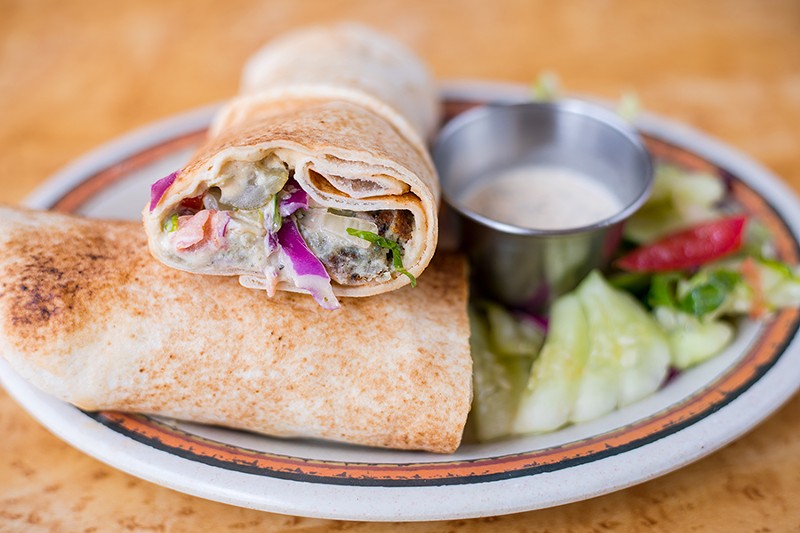 The falafel sandwich is topped with onion, parsley, pickles and tahini. - MABEL SUEN