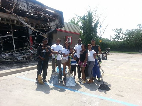 Volunteers clean at the QuikTrip after riots on Sunday night. Erica Hampton is in the middle holding a shovel. - KATHRYN BANKS
