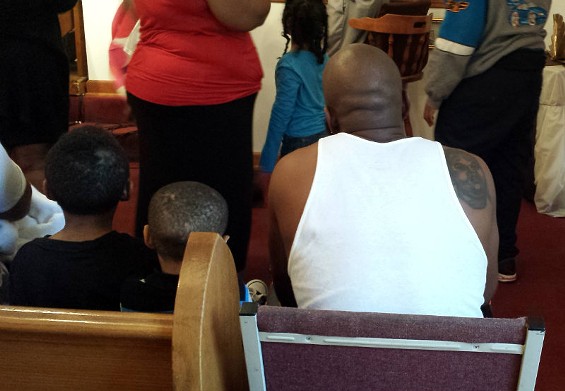 Michael Brown Sr. waits his turn to get baptized. On his right shoulder is a tattoo of his son. - Jessica Lussenhop