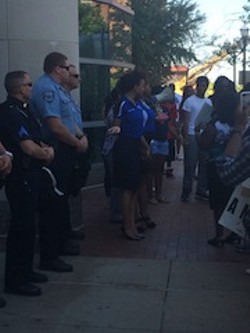 Protester extends a hand in prayer to a Clayton police officer. - Photo by Mitch Ryals