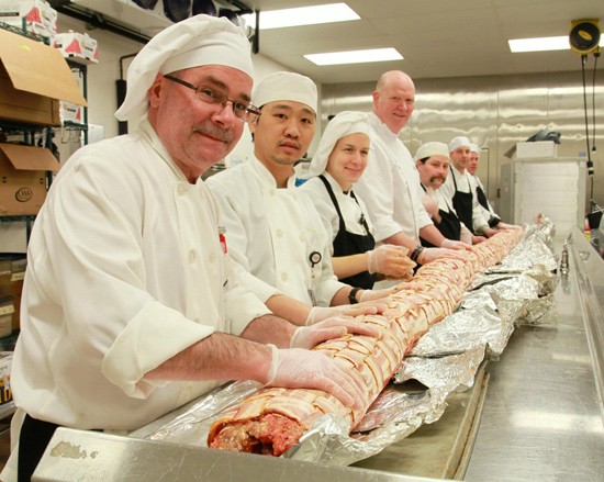 Chef John Johnson (fourth from left) and staff with a 200-pound trial run of a hog log. - IMAGE VIA