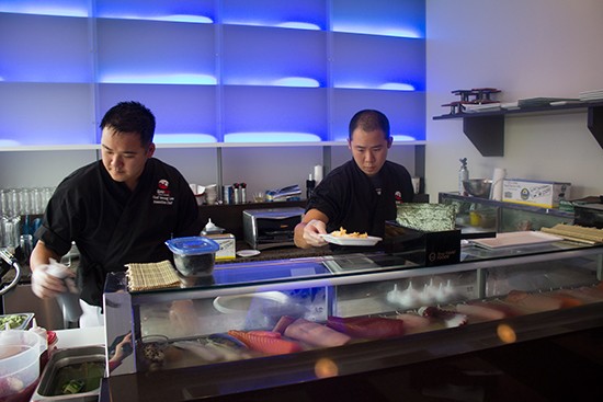 Chef Soung Lee prepares dishes at the sushi bar with another chef.