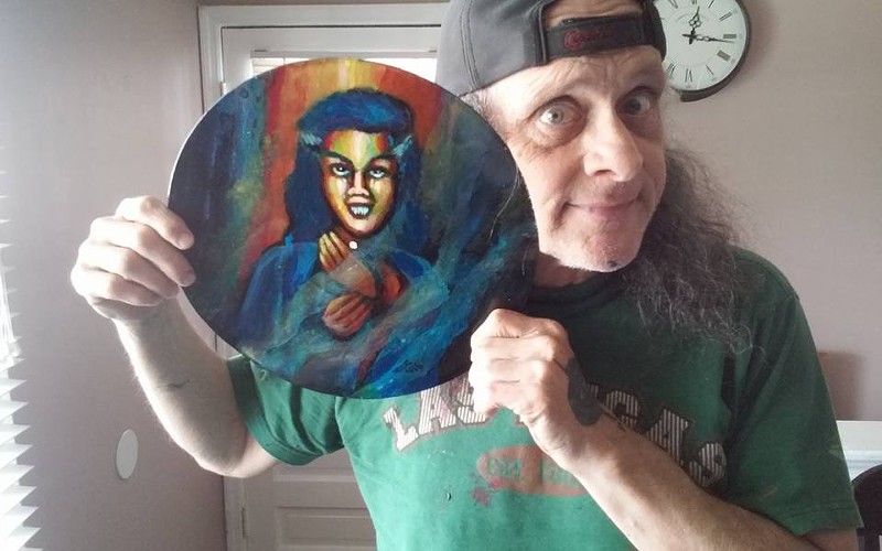 Wayne St. Wayne posing with some of his art.