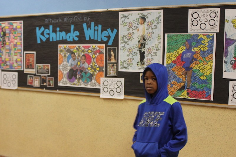 Jaran May poses in front of his artwork, now hanging on the walls of Bryan Hill Elementary School. - SARAH FENSKE
