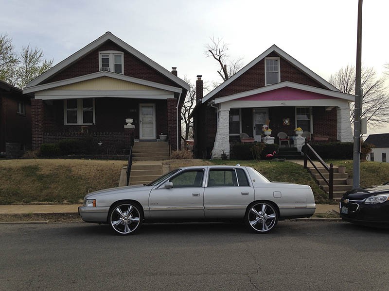 James Cobb's Cadillac parked in front of the Bevo Mill house (right) where he grew up. - PHOTO BY DOYLE MURPHY