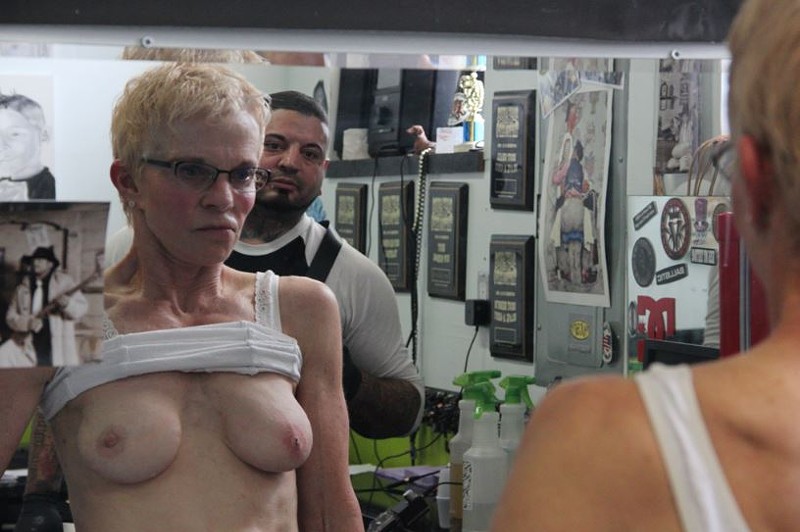 Catalano hovers while Kilhoffer inspects the newly implanted diamond stud in her right breast.
