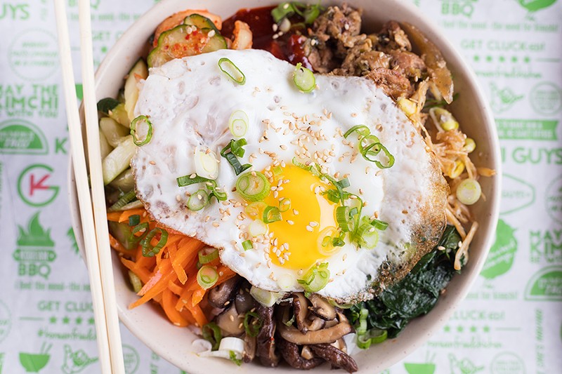 The bibimbap bowl is topped with green onions, sesame seeds, sesame oil and a fried egg. - MABEL SUEN