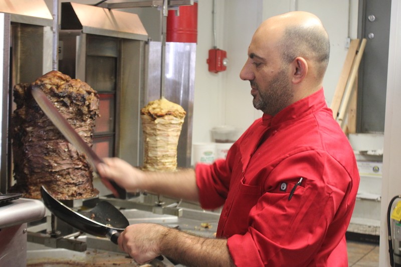 Rasheed Al Nwateer works the rotisserie, which is visible from the front counter. - PHOTO BY SARAH FENSKE