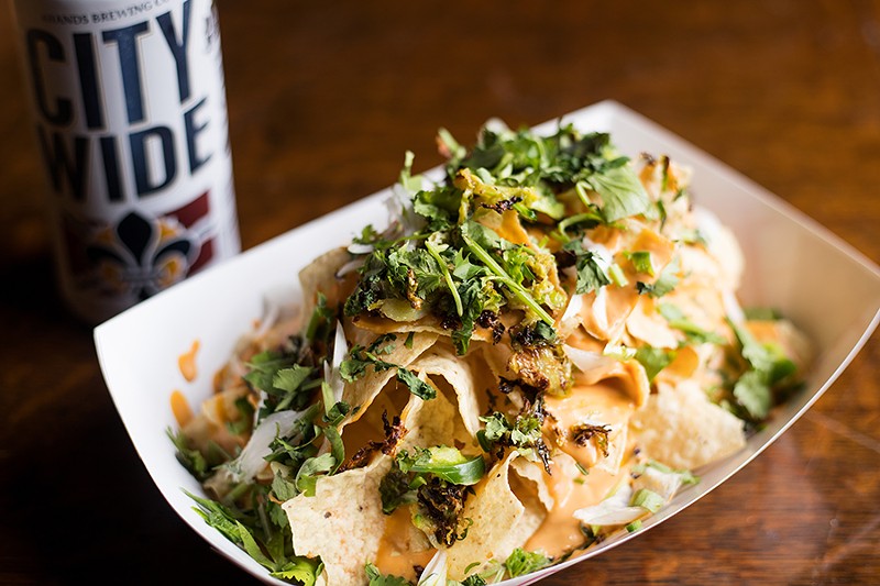 Nachos are topped with sautéed Brussels sprouts, green onion, jalapeños, cilantro and cheese sauce. - MABEL SUEN