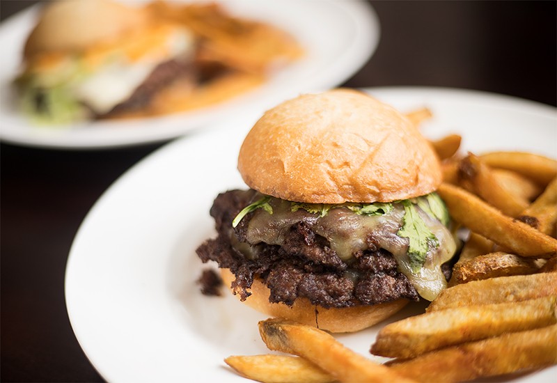 The three-stack burger is topped with micro arugula and "Carmeo" onions and smothered in raclette cheese. - MABEL SUEN