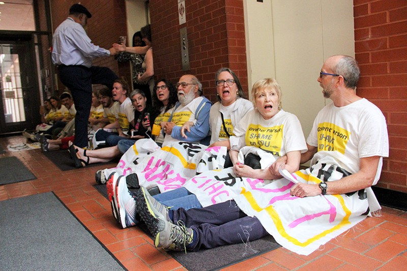 A state employee steps over a line of protesters blocking the elevators in the Wainwright Building. - DANNY WICENTOWSKI