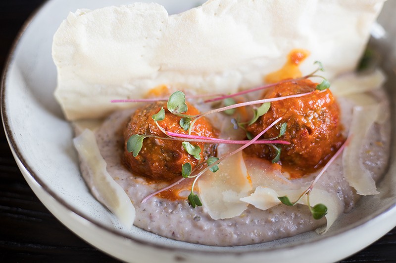 Lamb meatballs are tender and spiked with heat, but the plate’s real highlights are the shockingly creamy grits and lavash crackers made with lamb fat. - MABEL SUEN