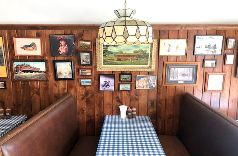 The dining room features wood paneling, retro framed artwork and vintage stained glass light fixtures. - Liz Miller