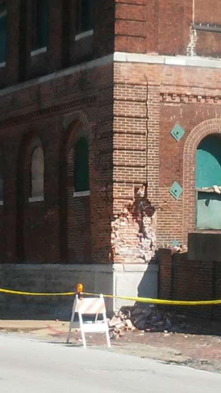 A crack runs up the side, and bricks lie on the street two days before the partial building collapse. - AARON P. BURY