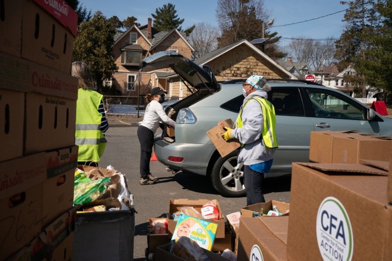 Volunteers load food packages into clients’ cars in Englewood, New Jersey. - CAROLINE GUTMAN / FOR KHN