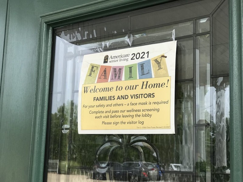 A sign hangs outside the entrance to The Neighborhoods by TigerPlace in Columbia, Missouri, letting visitors know a face mask and screening is required. - TESSA WEINBERG/MISSOURI INDEPENDENT