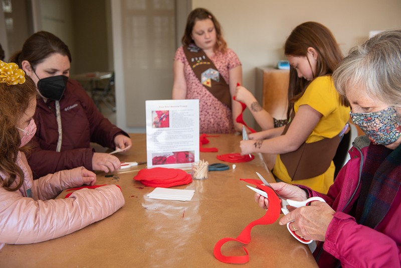 Girl Scouts and visitors gather in the Kranzberg Education Lab to make more roses for the sculpture. - Vu Phong