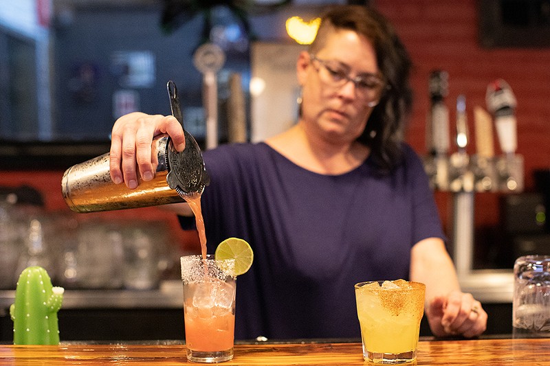 A woman bartender pours a drink.