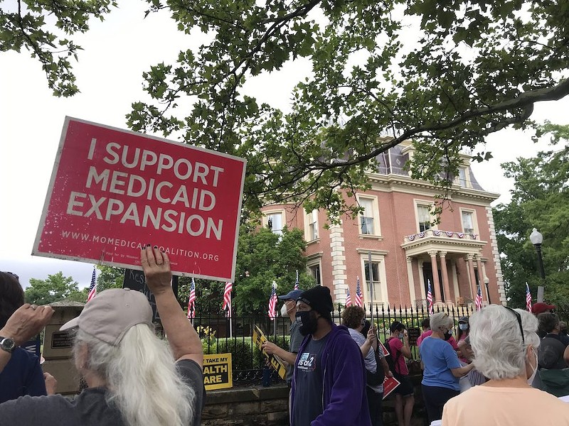 Demonstrators stand outside of the Governor’s Mansion in Jefferson City on July 1, 2021 and hold signs urging Gov. Mike Parson to fund voter-approved Medicaid expansion.