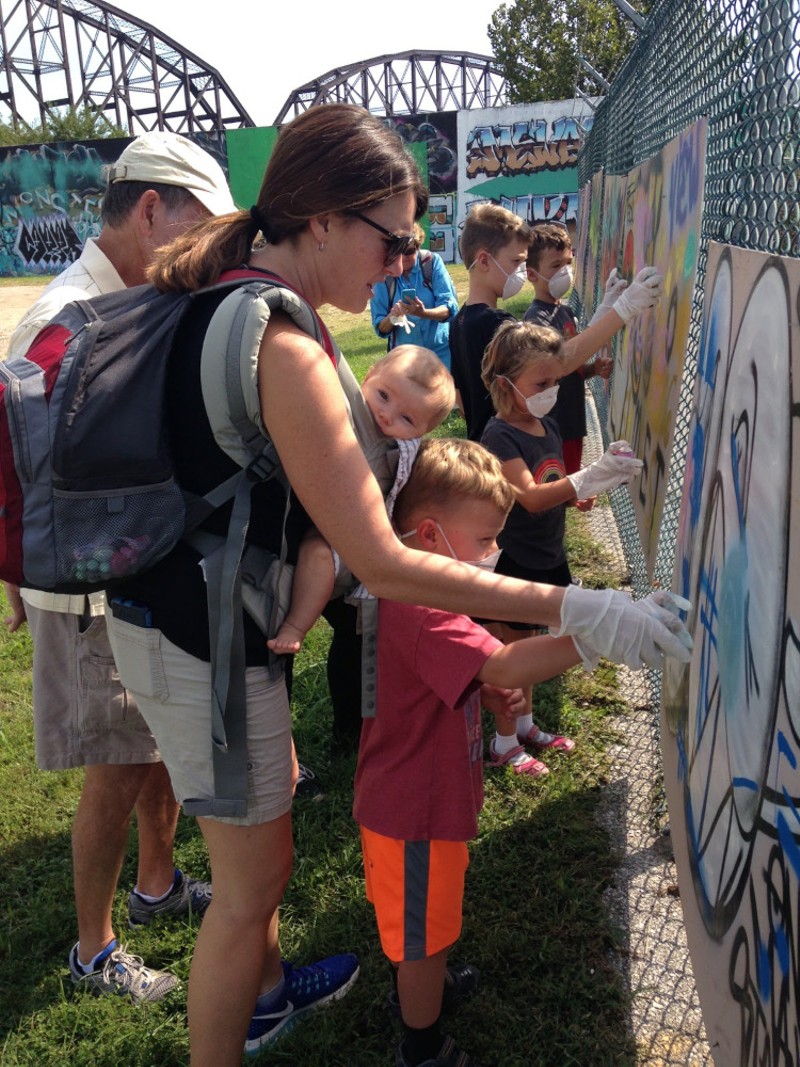Parents and their children contribute to the graffiti murals as part of Paint Louis.