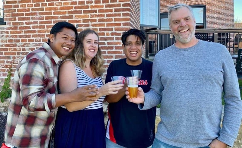Joel Crespo, Rachel Alcantara, Arnold Alcantara and Brian Hardesty hold beverages in front of a brick house.