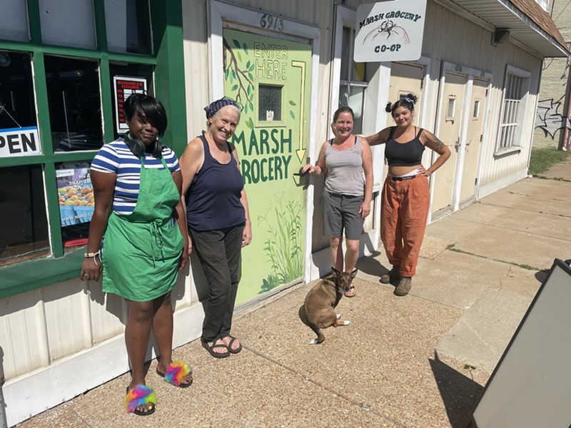 Ranata Frank, Beth Neff, Chrissy Kirchhoefer and Grace Smith stand on a sidewalk in front of a green door that reads "MARSH GROCERY."