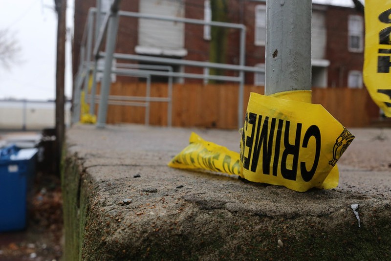 Yellow crime scene tape is wrapped around a pole.