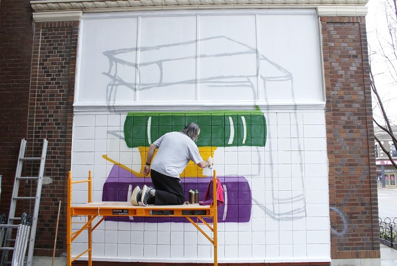 David Ruggieri spray paints the beginning of a mural of banned books in South City.  - Monika Obradovic