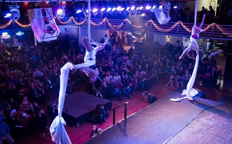 Acrobatic dancers perform over a crowded hall.