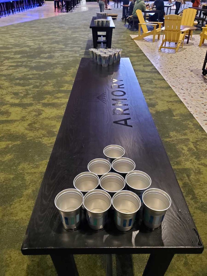 There are many tables set up with receptacles to hold beer pong cups.