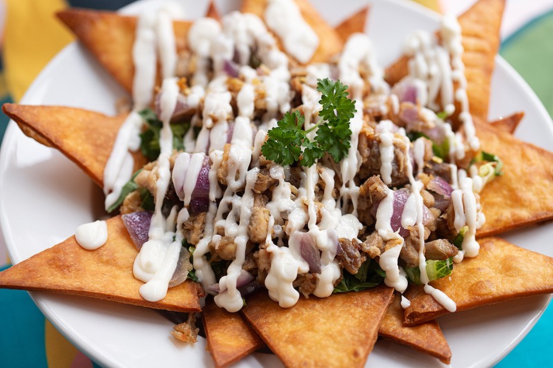 Sisig nachos are served on a bed of fried tortillas.
