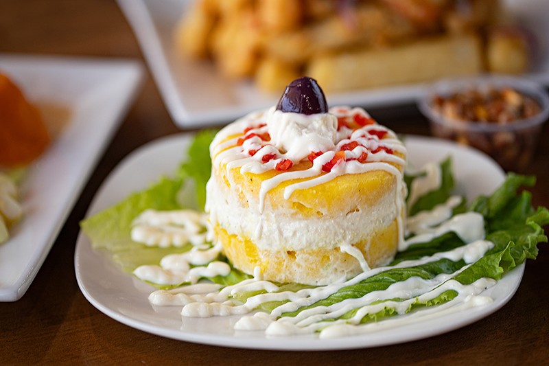 Causa limeña is creamy layers of mashed potato filled with shredded chicken, chopped vegetables and mayo.