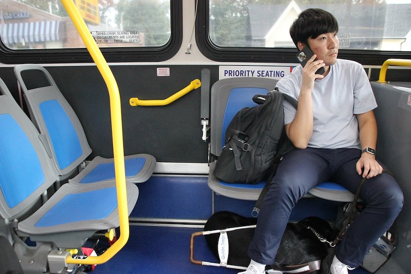 Seyoon Choi rides the bus to work with his trusty service dog resting under his seat. - KATHLEEN LEES