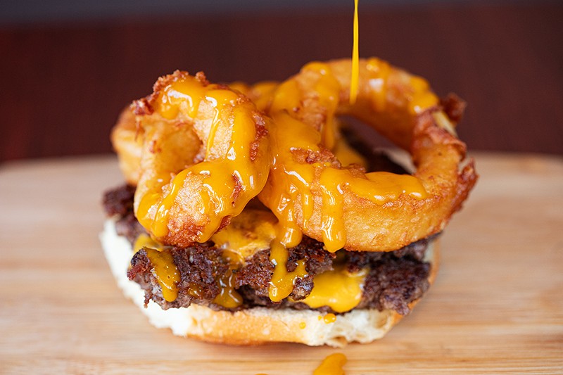 The Carolina Cowboy is a double cheeseburger topped with Carolina gold barbecue sauce and onion rings.
