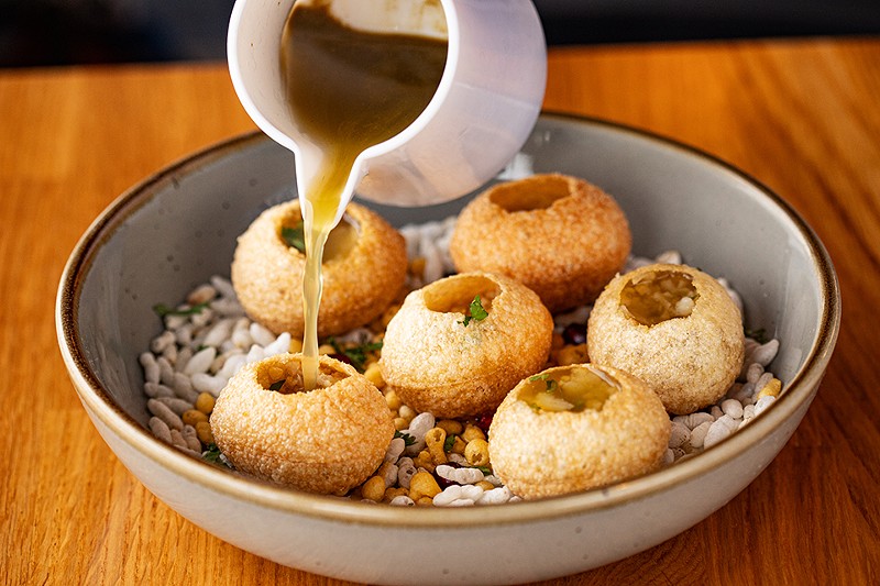 Pani puri, or crispy fried puffs, are filled with seasoned potato, chickpeas and shallots.