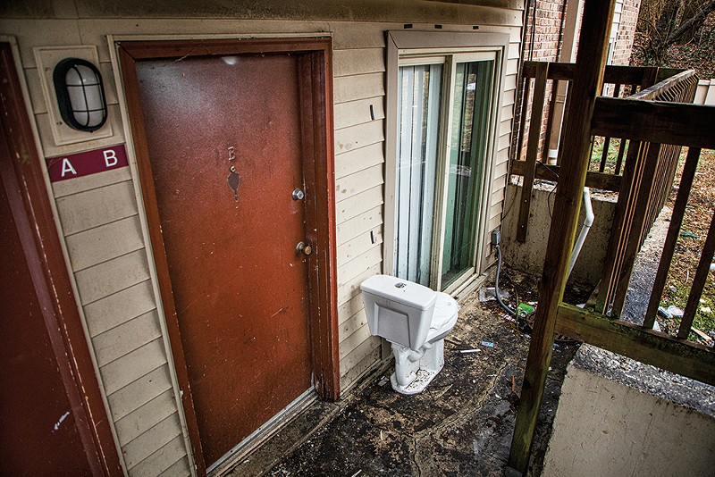A toilet stands sentinel over a trash-strewn walkway outside a vacant unit in Pleasant View Gardens. - ZACHARY LINHARES