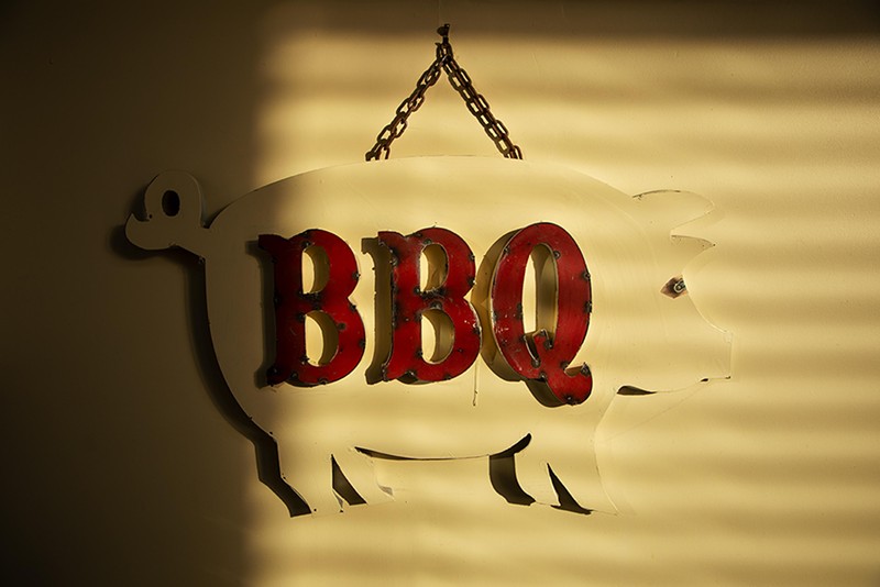 Sunlight shines on a barbecue sign at the front entrance of the Shaved Duck. - ZACHARY LINHARES