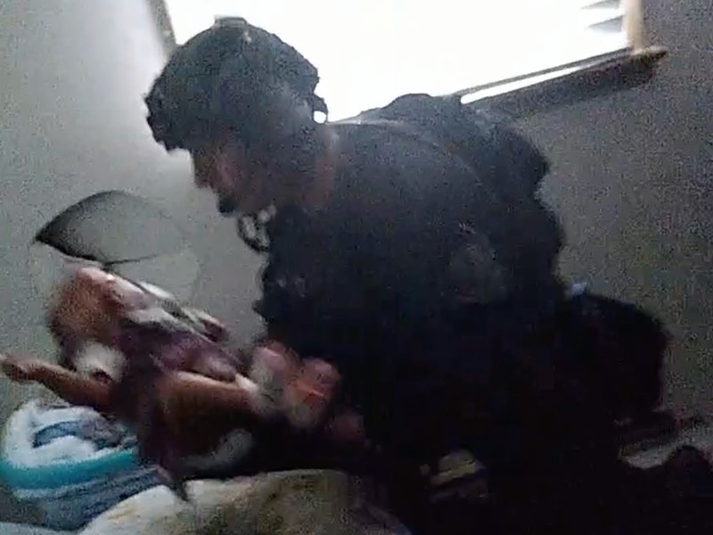 An officer carrying three-month-old baby after errant SWAT raid at Ferguson family's home.